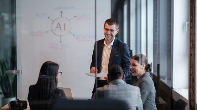 Diverse business team in a modern office during a meeting, discussing artificial intelligence strategy. Concept of AI innovation, teamwork, leadership, corporate planning, professional collaboration.